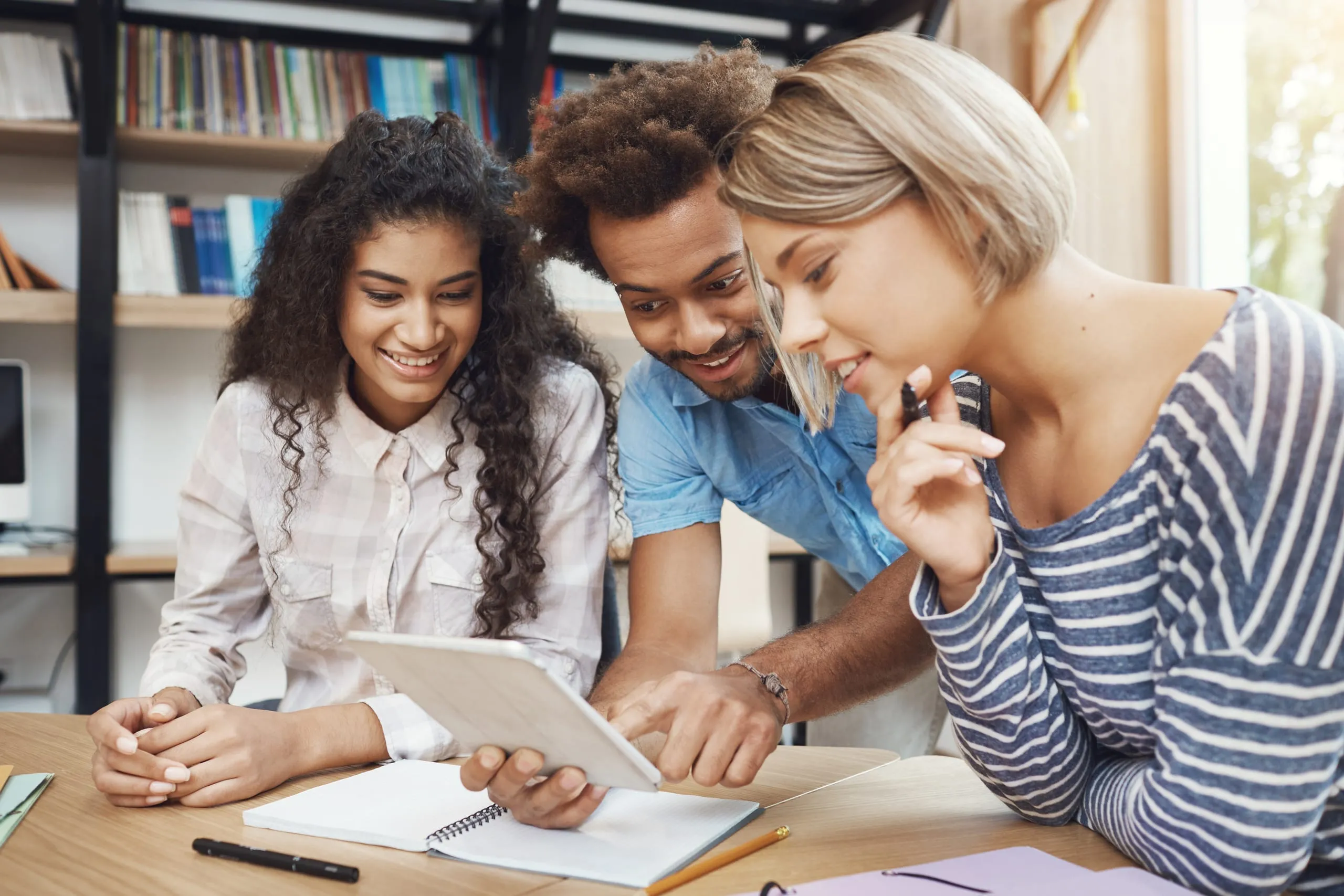 Trois apprenants travaillent ensemble autour d'une tablette dans un espace de formation.