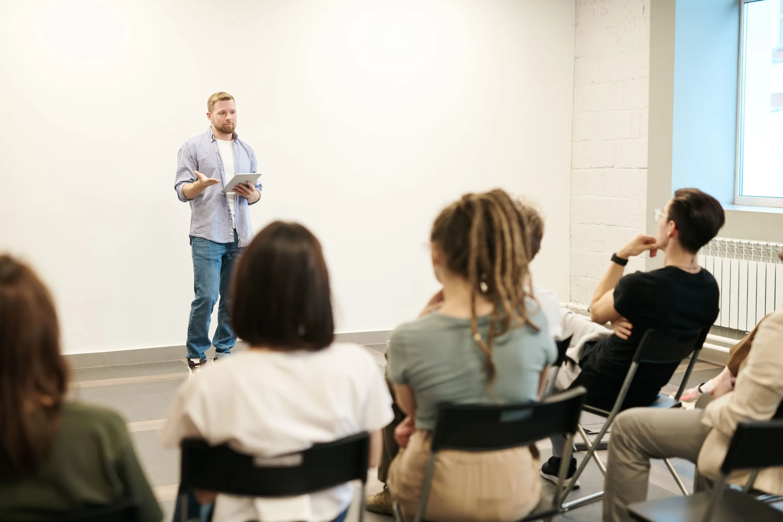 Formateur animant une session de formation professionnelle devant un groupe d'adultes.
