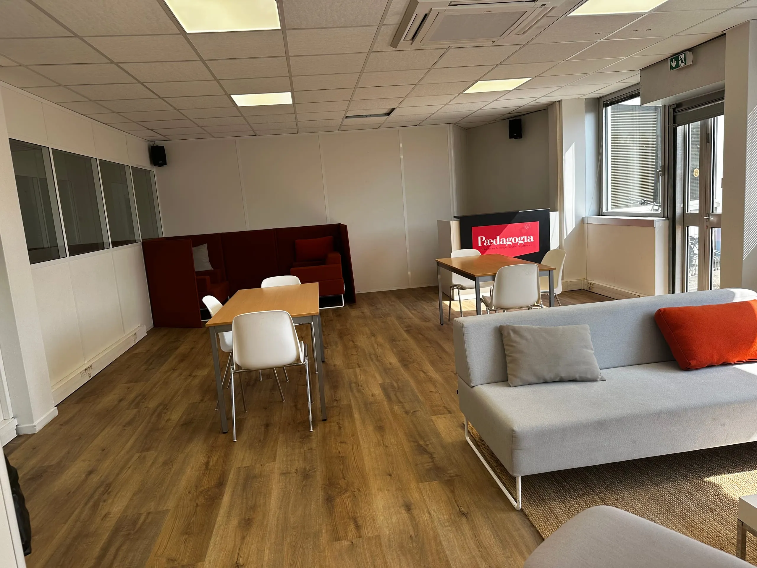 Espace commun polyvalent du CFA Paedagogia à Toulouse avec canapé, tables de travail et écran affichant le logo de l'organisme.