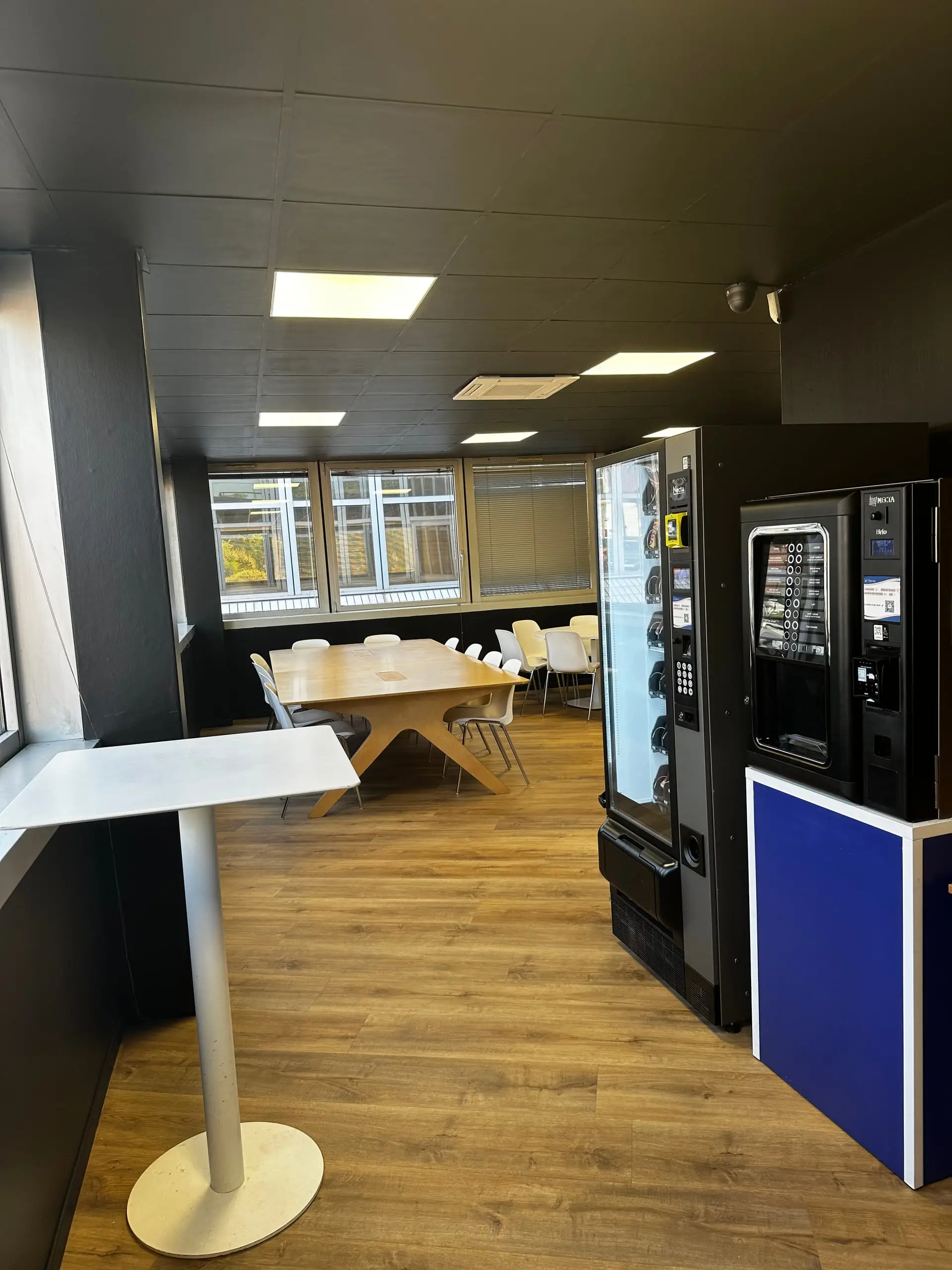 Cafétéria du CFA Paedagogia avec table en bois et distributeurs automatiques