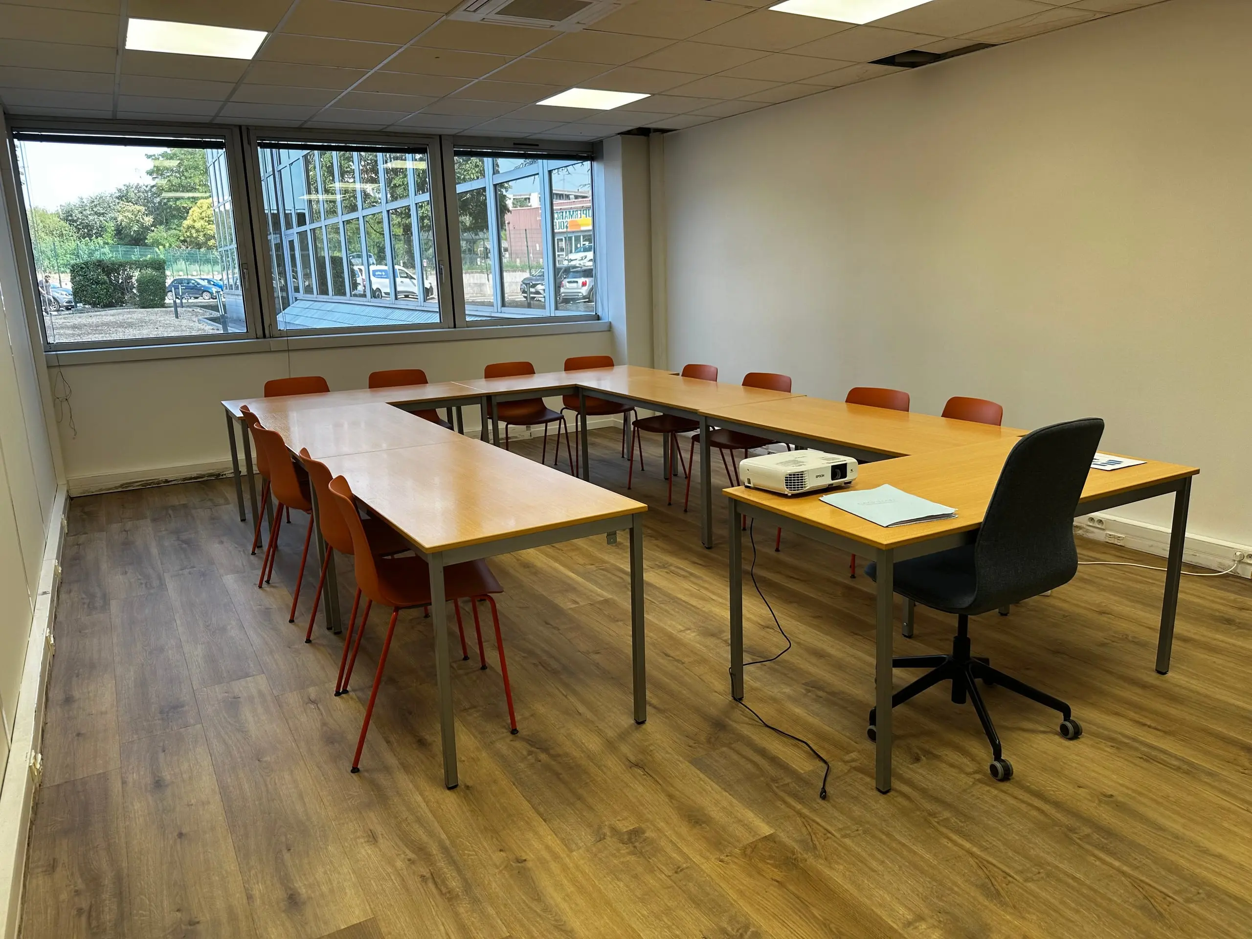 Salle de formation du CFA Paedagogia avec tables en U, chaises colorées et projecteur