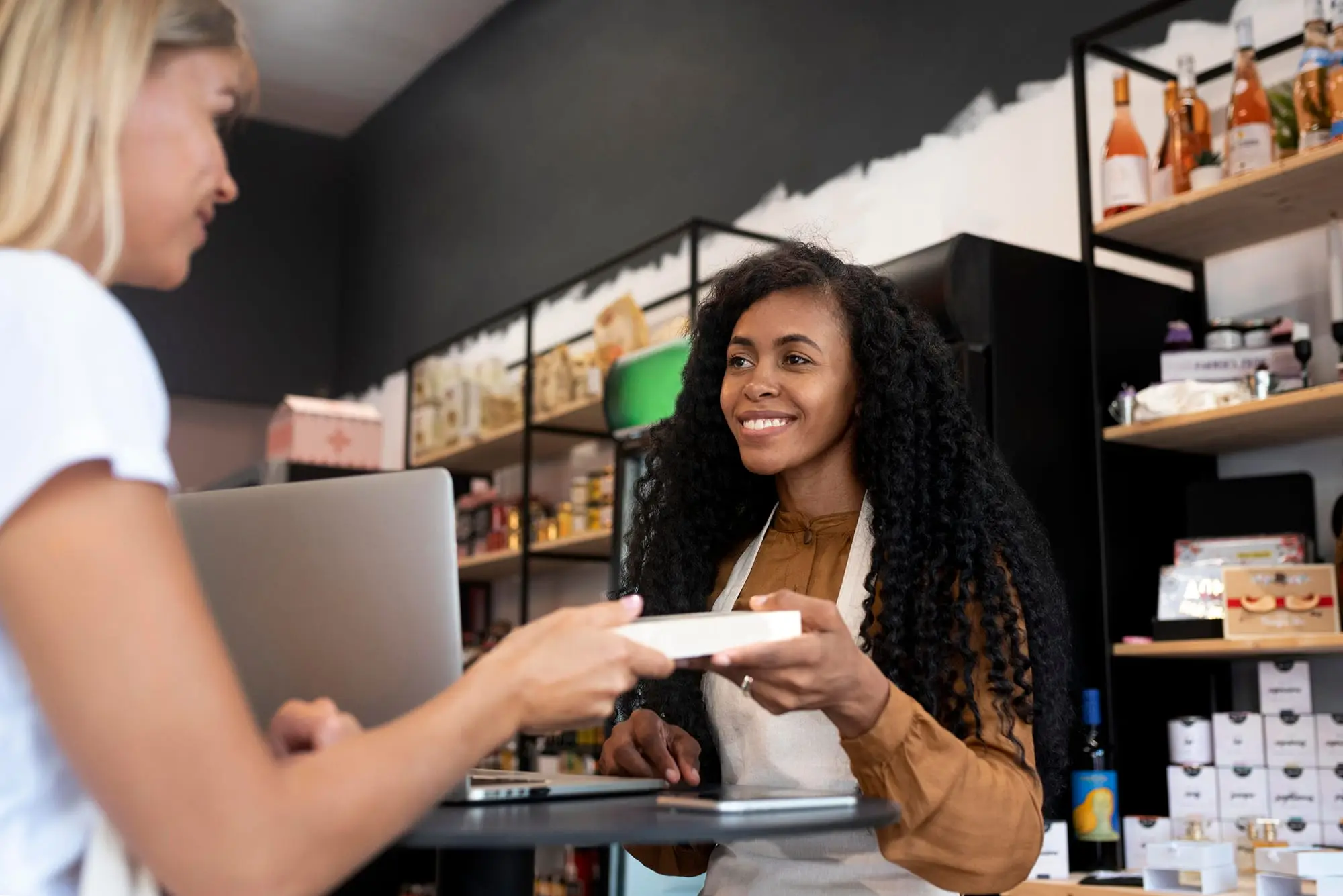 Conseillère de vente souriante remettant un article à une cliente en boutique