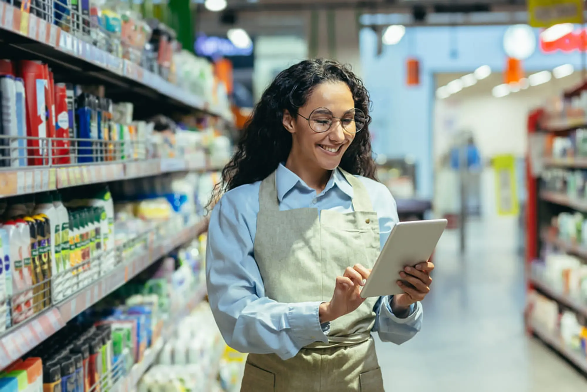 Responsable d'établissement marchand consultant sa tablette dans un rayon de supermarché