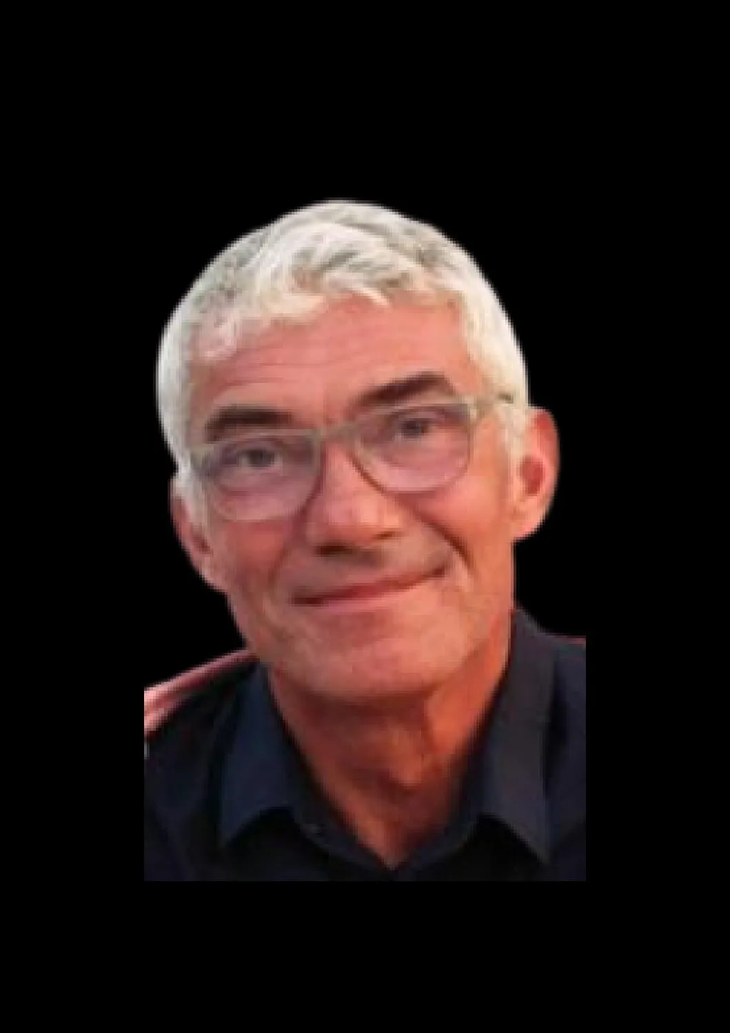 Portrait de Yann Hamon souriant, avec des lunettes et une chemise sombre sur fond noir